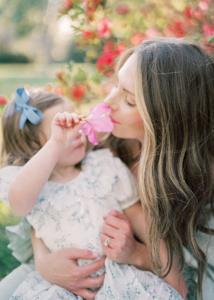 mother holding little girl smelling flowers at hampton park