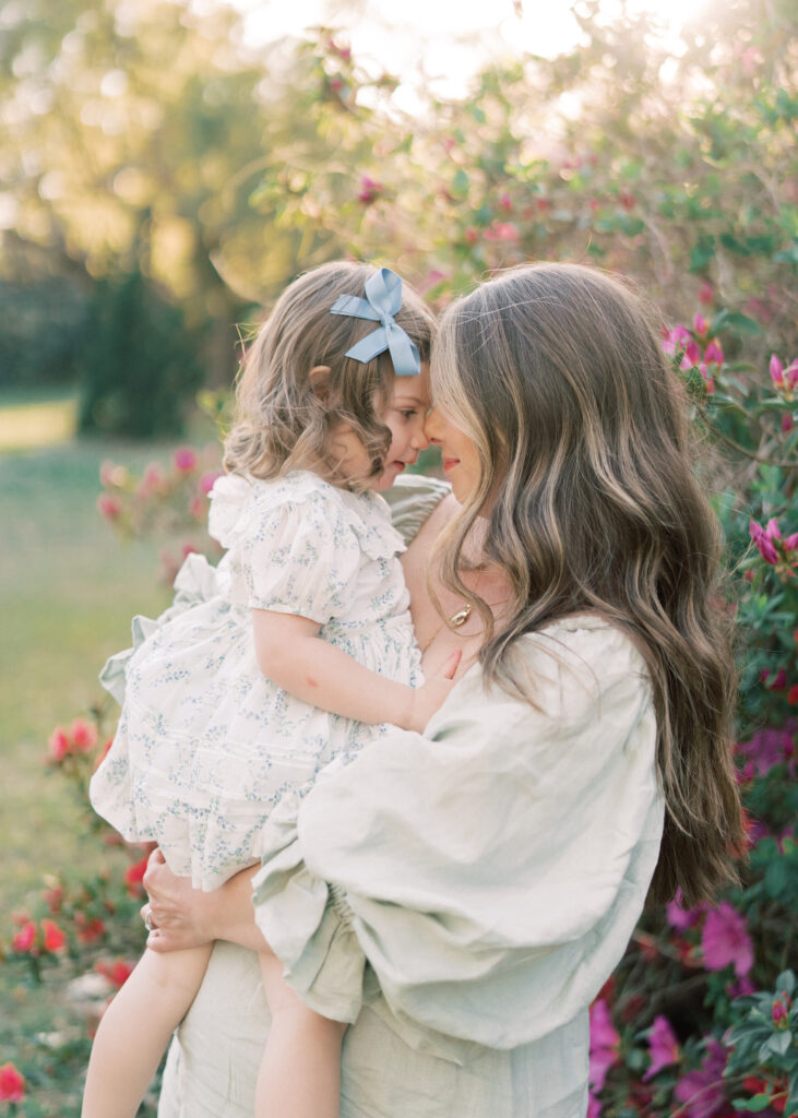mother holding daughter surrounded by flowers
