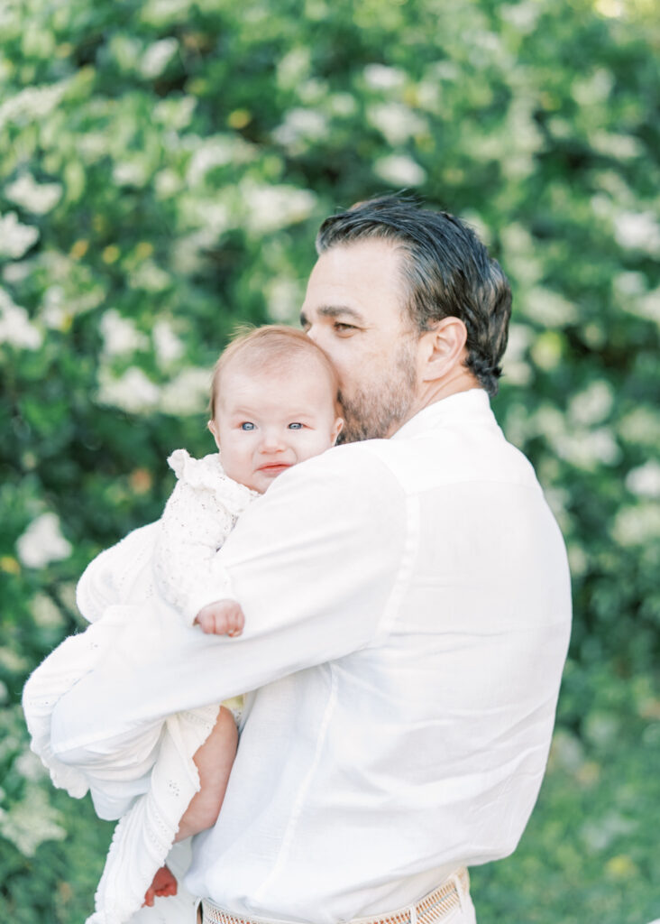 dad holding baby wearing all white