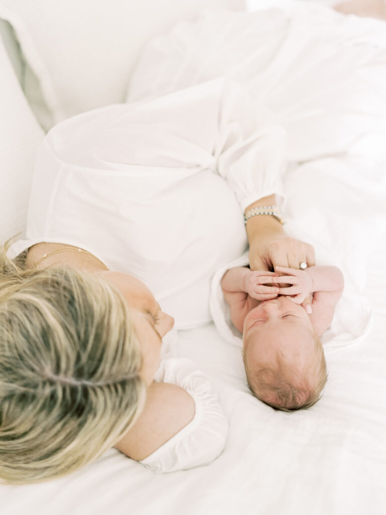 mom laying on bed with newborn in home
