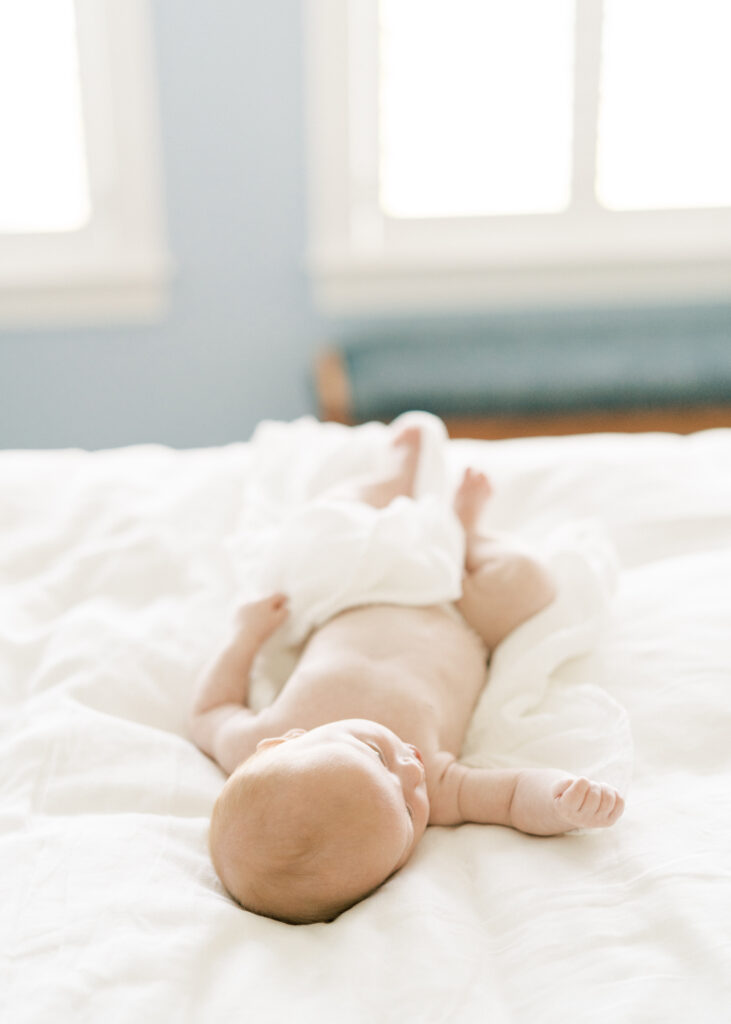 newborn laying on bed in home