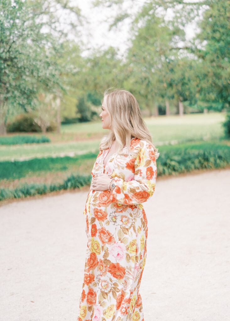 mom holding baby bump at park in floral dress
