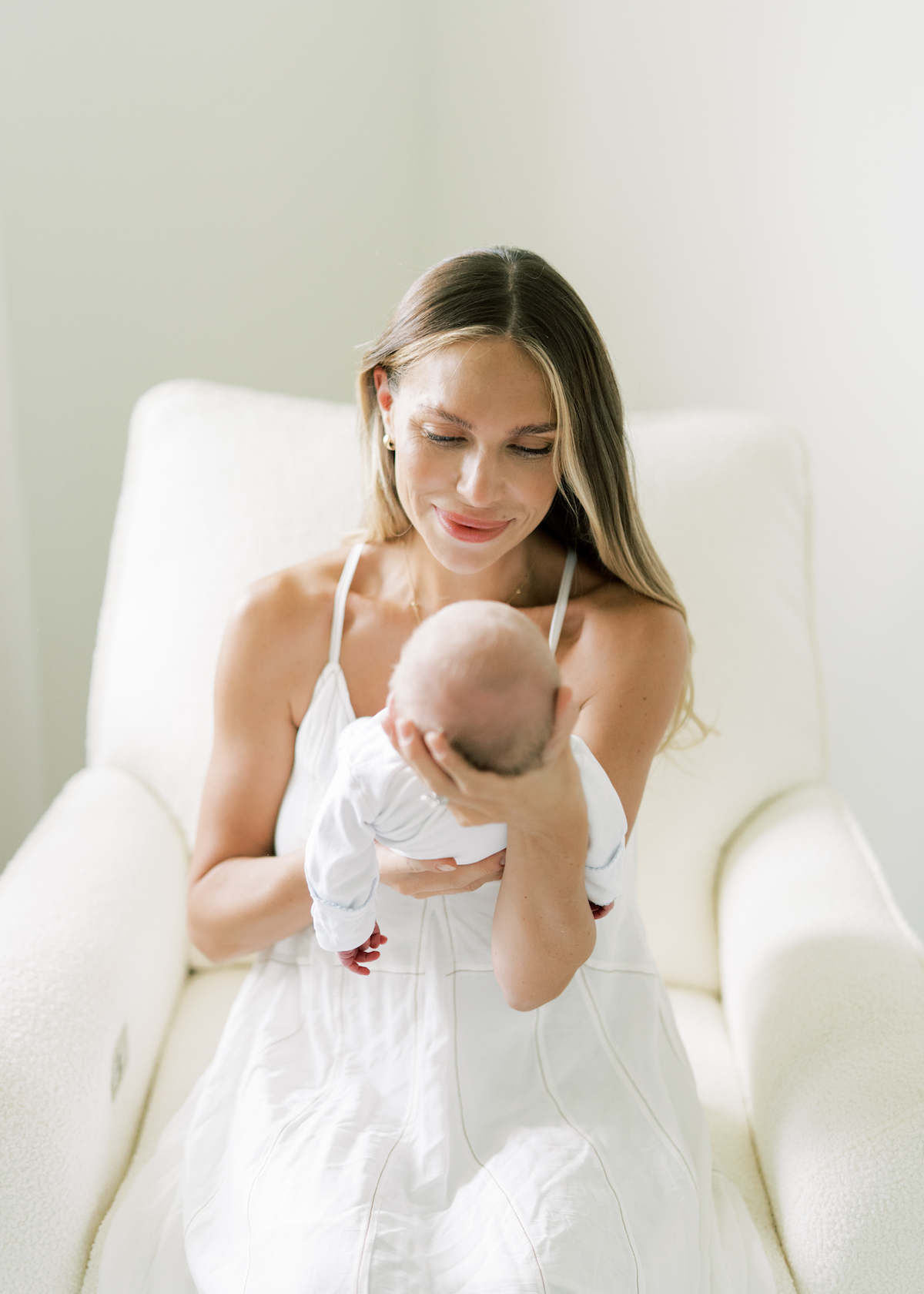 mom holding baby in nursery wearing white dress